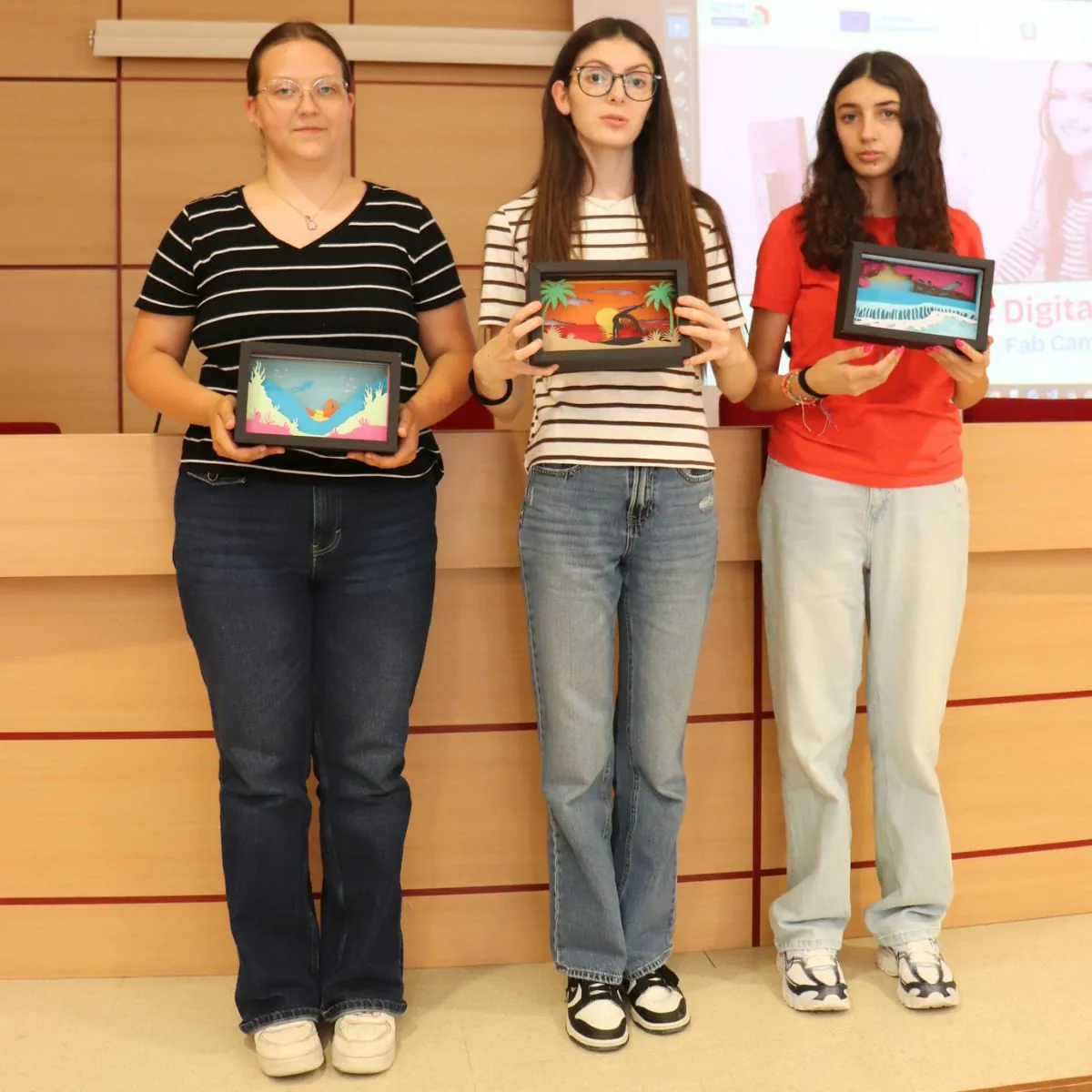 Tre partecipanti mostrano i diorami realizzati durante Ragazze Digitali 2026.